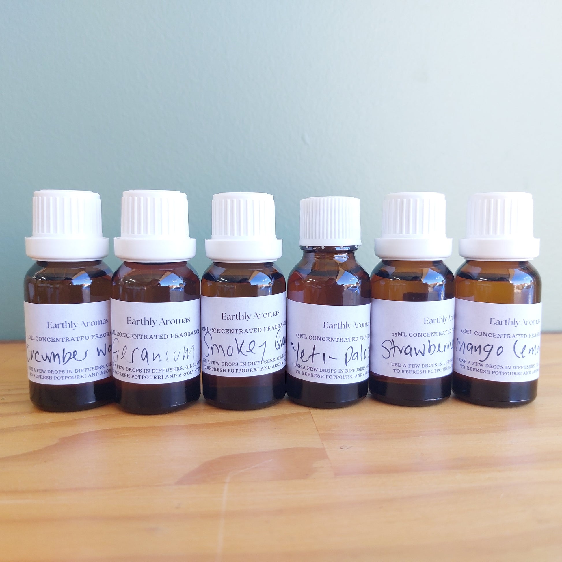 Set of Earthly Aromatics Fragrance oil bottles on a wooden surface with a light blue background